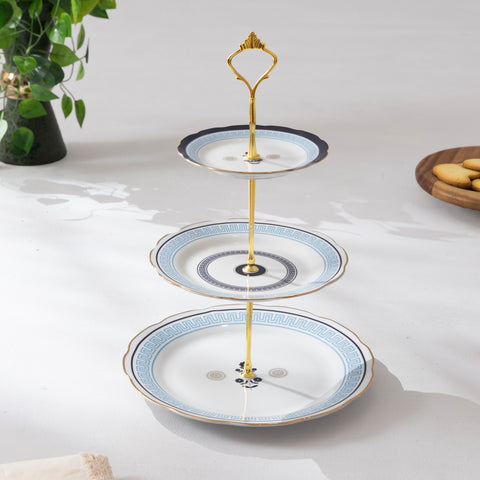 Three-tiered ceramic serving tray with gold accents on a white surface.