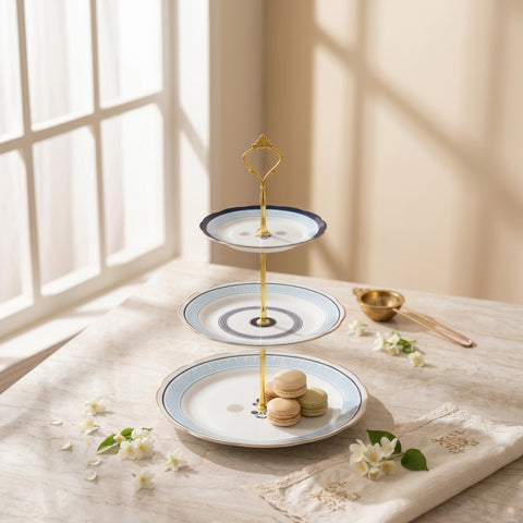Three-tiered ceramic dessert stand with macarons on a table with sunlight streaming through a window.