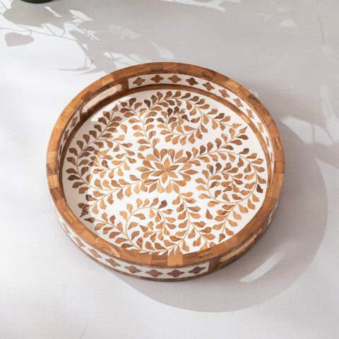 Decorative wooden bowl with intricate carvings on a white surface