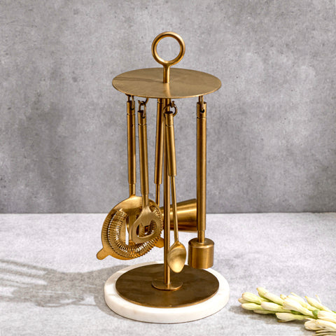 Brass cocktail bar set with strainer, jigger, muddler and tongs shown from the front