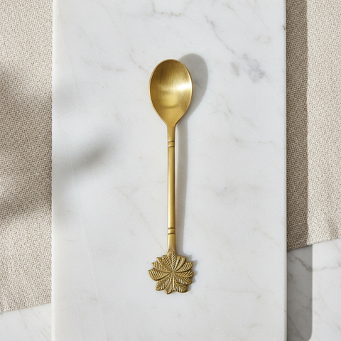 Brass serving spoon with decorative handle on a marble surface