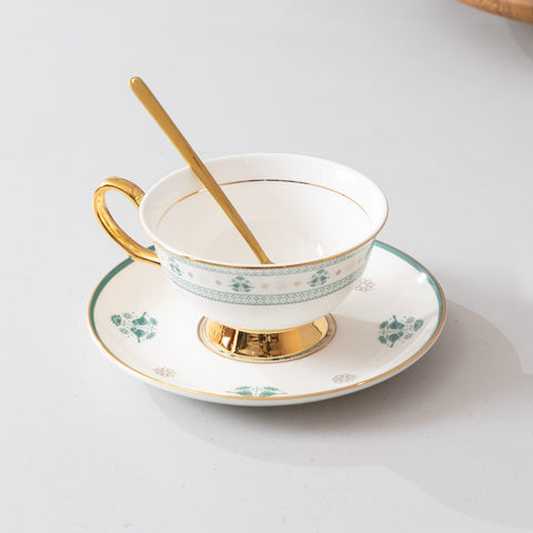 Teacup with gold handle and saucer on a white background