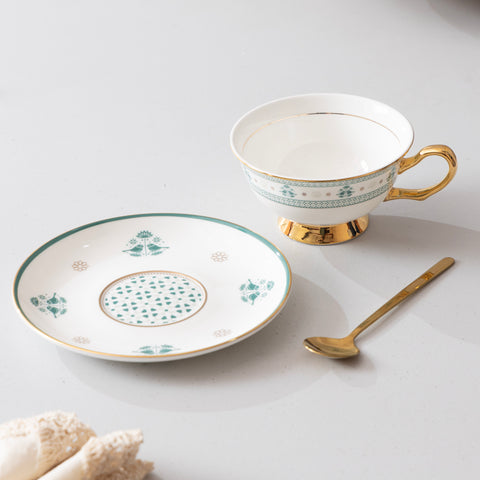Teacup, saucer, and spoon with decorative patterns on a light background