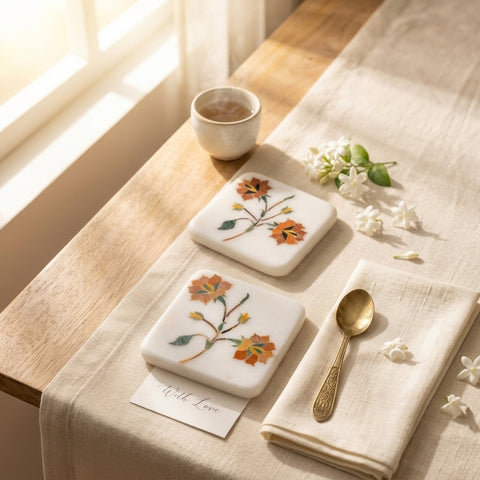 Two floral coasters on a table with a cup, spoon, and card.