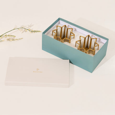 Gold geometric earrings in a light blue box on a white background