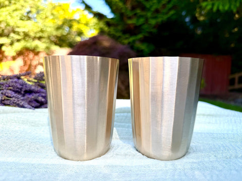 Close-up of the Kansa cup rim revealing the polished copper-tin finish