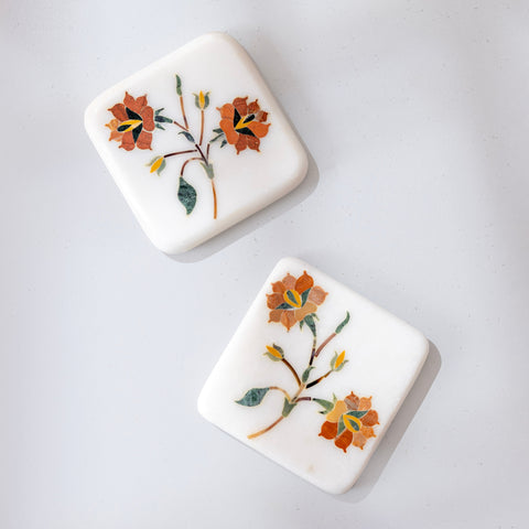 Two square ceramic coaster with floral designs on a white background