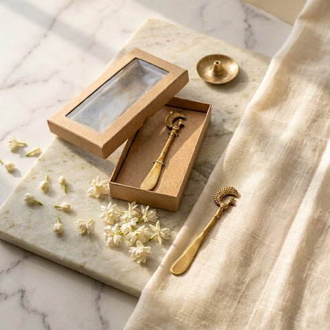 Gold spoon and decorative item on a marble surface with flowers and fabric.