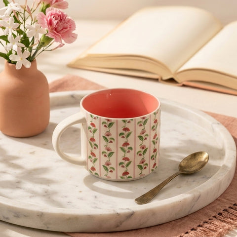 Patterned mug with red interior on a marble tray with flowers and book