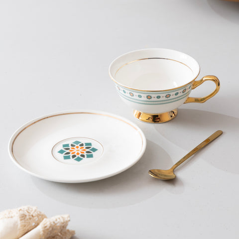 Ceramic teacup, saucer, and spoon with decorative patterns on a light background