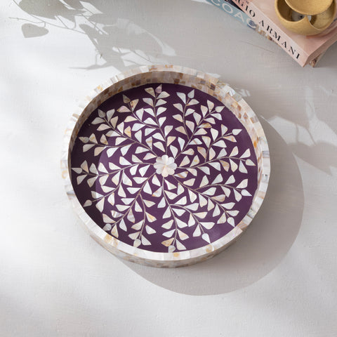 Decorative round tray with purple and white leaf pattern on a light surface