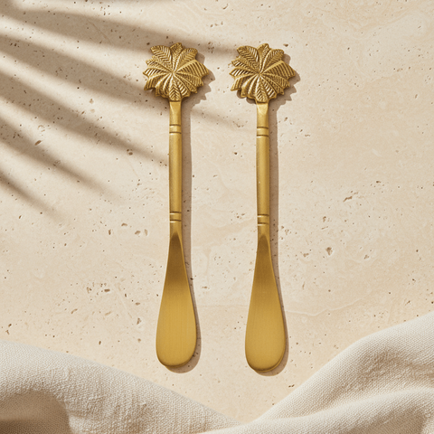 Brass butter knife set  with palm-tree handles on a beige surface