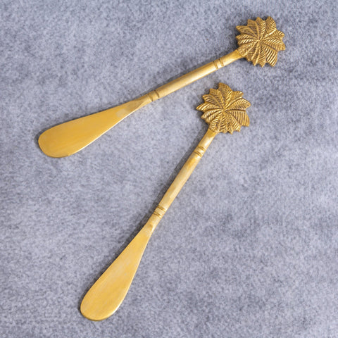 Brass butter knife set  with palm-tree handles on a gray surface