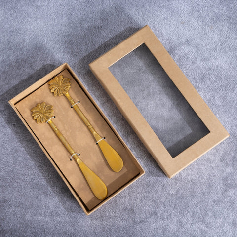 Brass butter knife set  with palm-tree handles in a cardboard box on a gray surface
