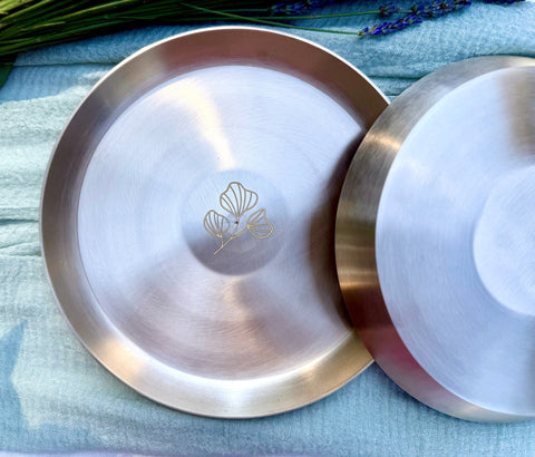 Two 6-inch Kansa plates showing the engraved floral motif and natural patina