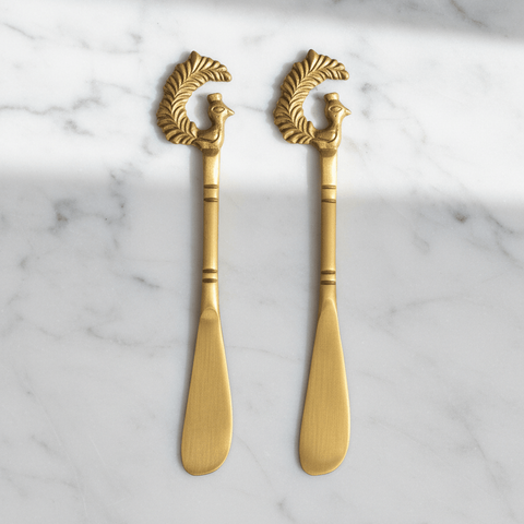 Two butter spreader knives on a marble surface