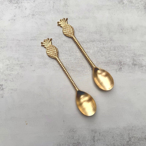 Two pineapple brass spoons displayed to show the polished design