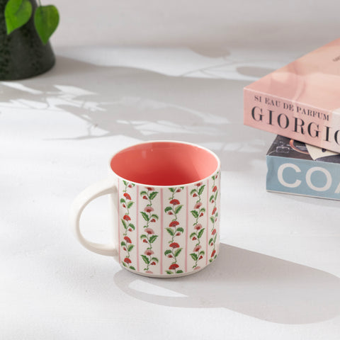 Mug with floral pattern on a light surface with books and a plant in the background