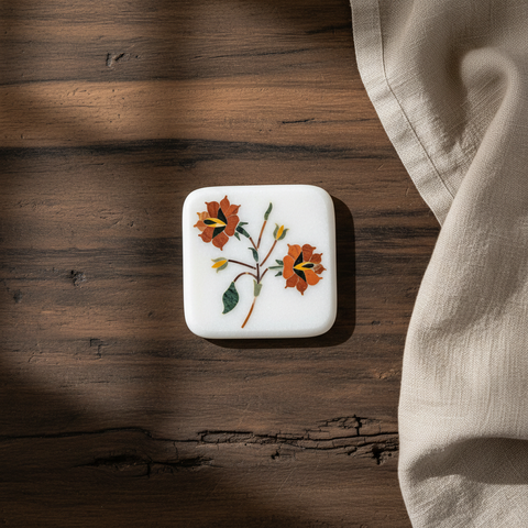 Square white object with floral design on a wooden surface