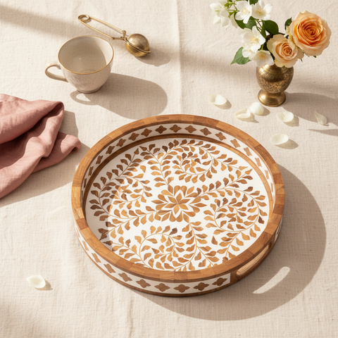 Decorative wooden tray with floral patterns on a table with a cup and flowers.