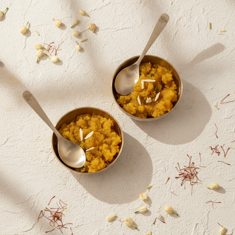 Two bowls of yellow dessert with saffron strands on a textured white surface