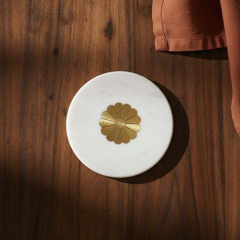 A white marble coaster with brass inlays on a wooden surface