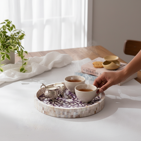 Person holding a teacup on a violet round tray with mother of pearl inlay.